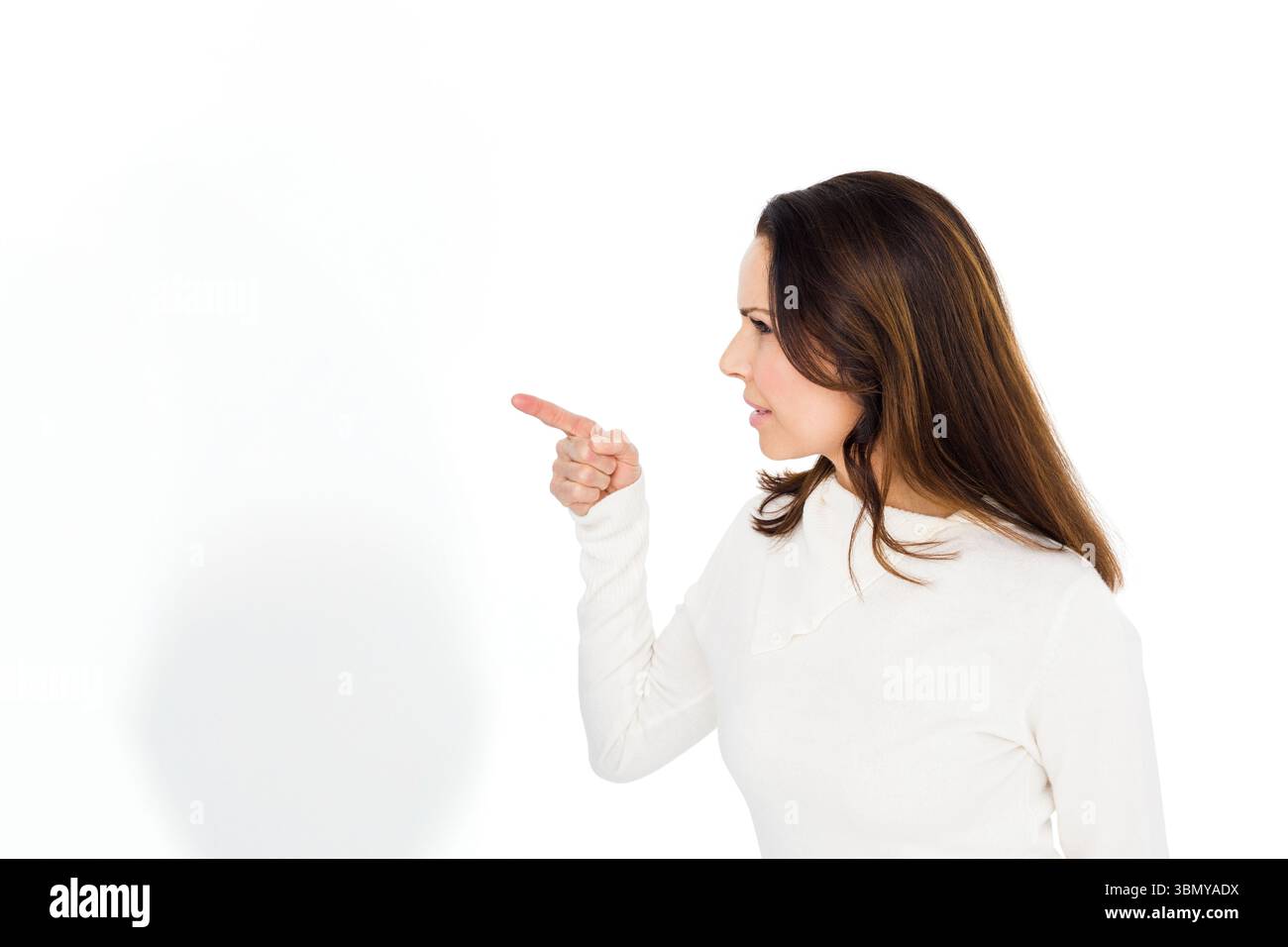 Donna che punta con la mano destra che indossa la parte superiore bianca in studio su sfondo vuoto, copia spazio Foto Stock