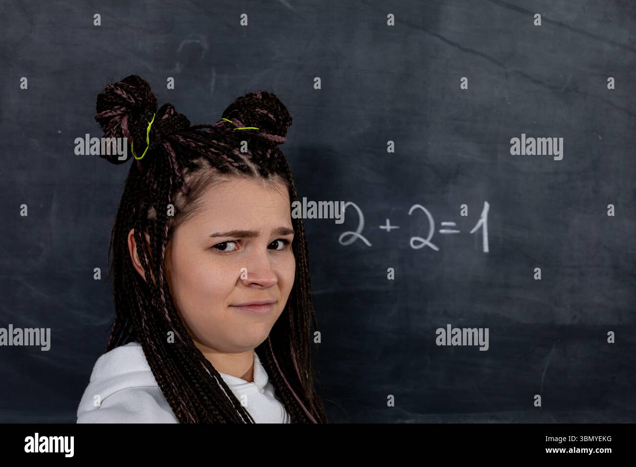 Uno studente confuso si trova davanti a un'equazione matematica errata sulla lavagna, perplesso Foto Stock
