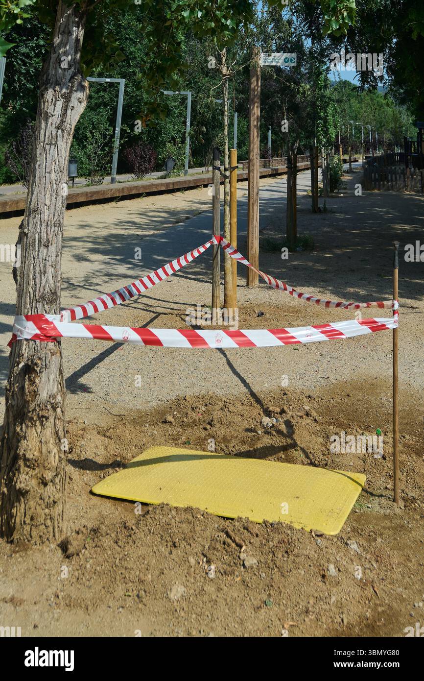 Cantiere all'interno di un parco con alberi giovani e barriere di sicurezza, che mettono in risalto gli sforzi di ecologizzazione urbana. Ideale per il trasporto di concetti di città p Foto Stock