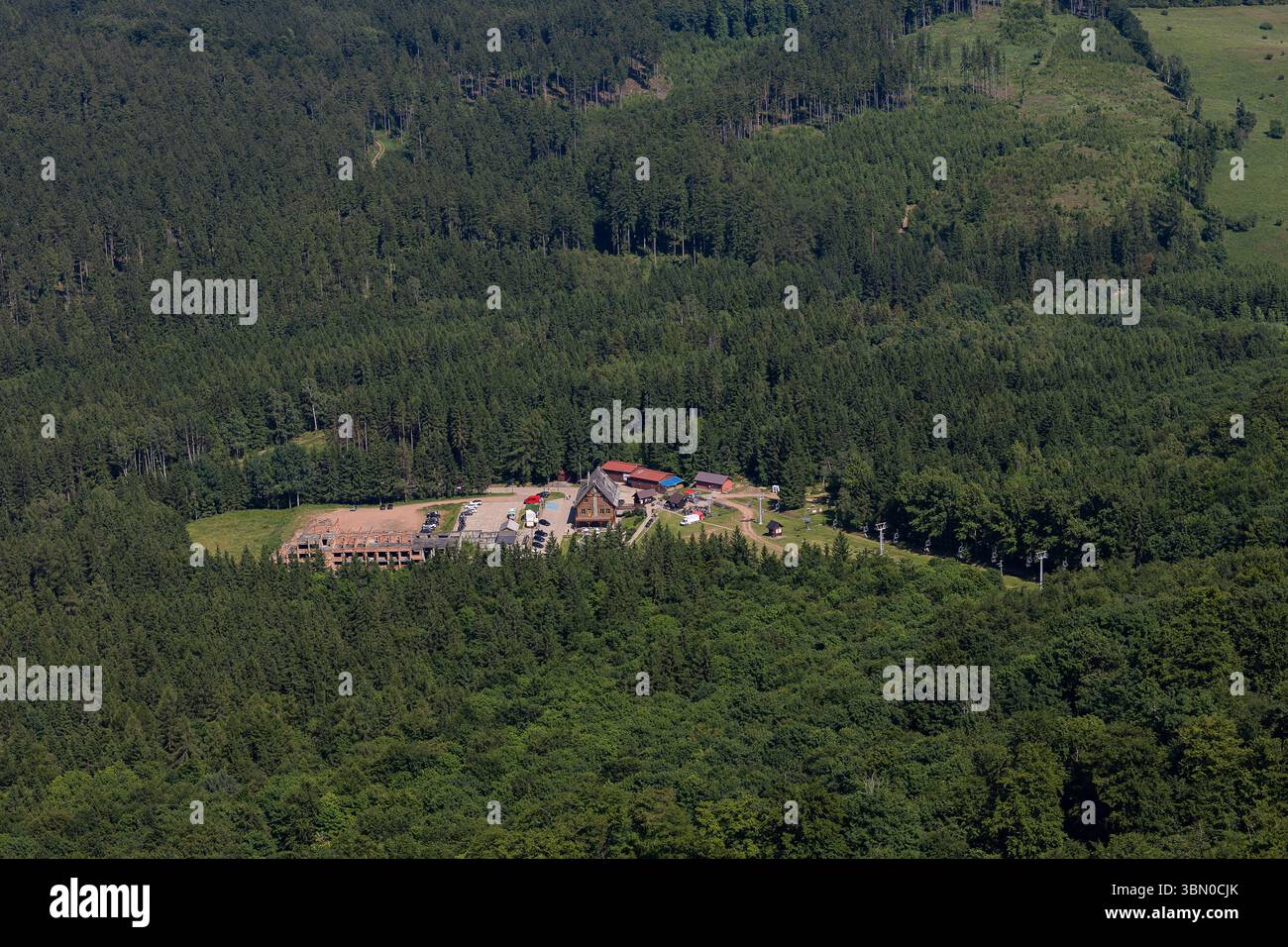 Vista aerea del rifugio di montagna nascosto nella fitta foresta con parcheggio e sentieri escursionistici. Turismo ecologico, stile di vita attivo e avventura all'aria aperta Foto Stock