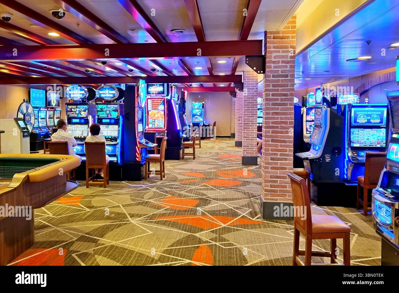 Casinò all'interno della lussuosa nave da crociera Emerald Princess con file di slot machine che illuminano uno spazio con luci blu e rosse. Foto Stock