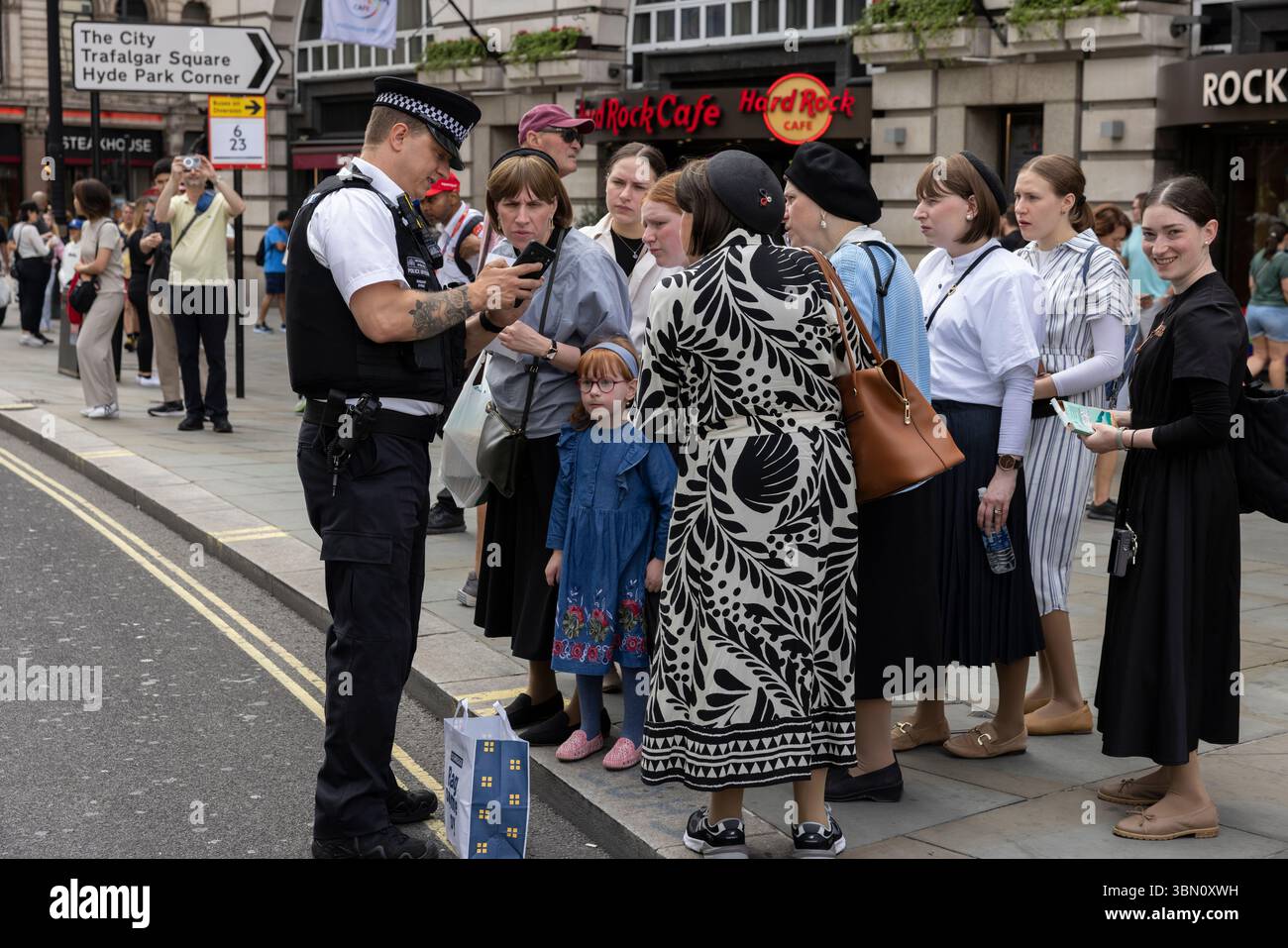 I turisti ebrei ricevono assistenza da un poliziotto metropolitano nel West End di Londra, Inghilterra, Regno Unito Foto Stock