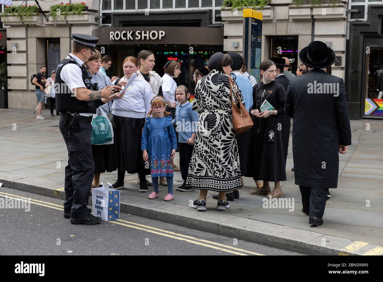 I turisti ebrei ricevono assistenza da un poliziotto metropolitano nel West End di Londra, Inghilterra, Regno Unito Foto Stock