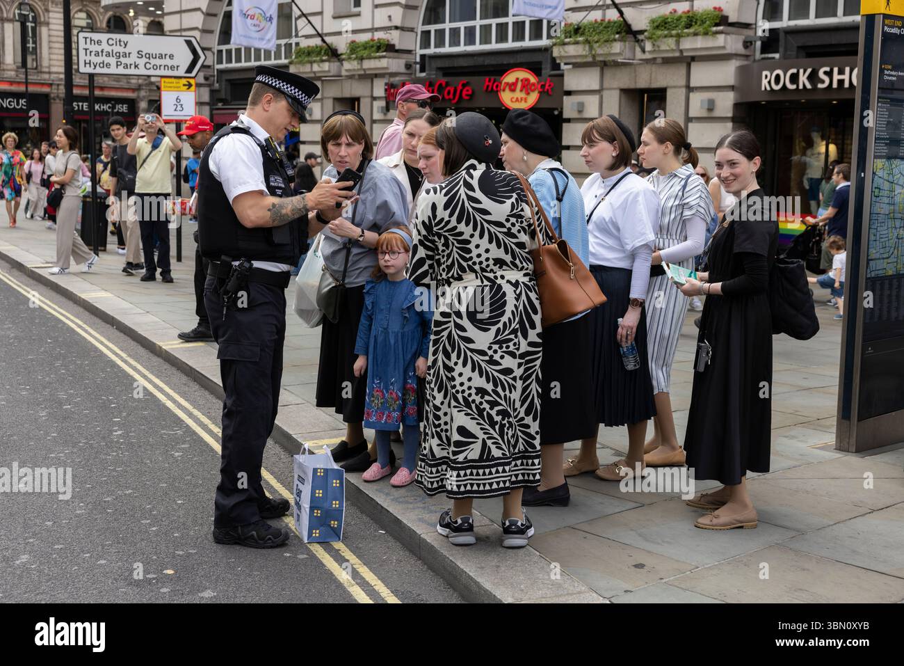 I turisti ebrei ricevono assistenza da un poliziotto metropolitano nel West End di Londra, Inghilterra, Regno Unito Foto Stock