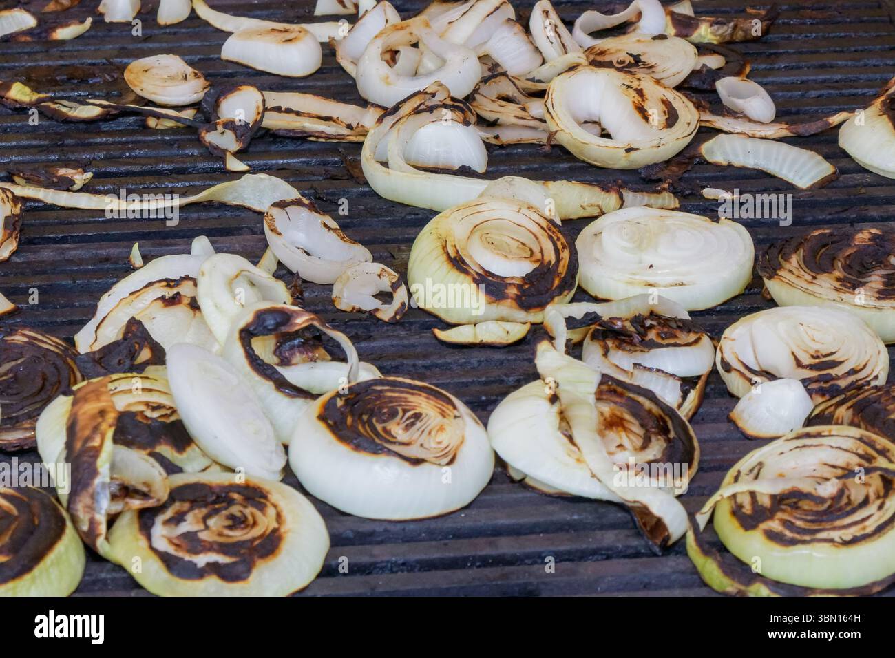 Le cipolle affettate vengono grigliate alla perfezione, sviluppando una ricca consistenza caramellata e un sapore più profondo. Foto Stock