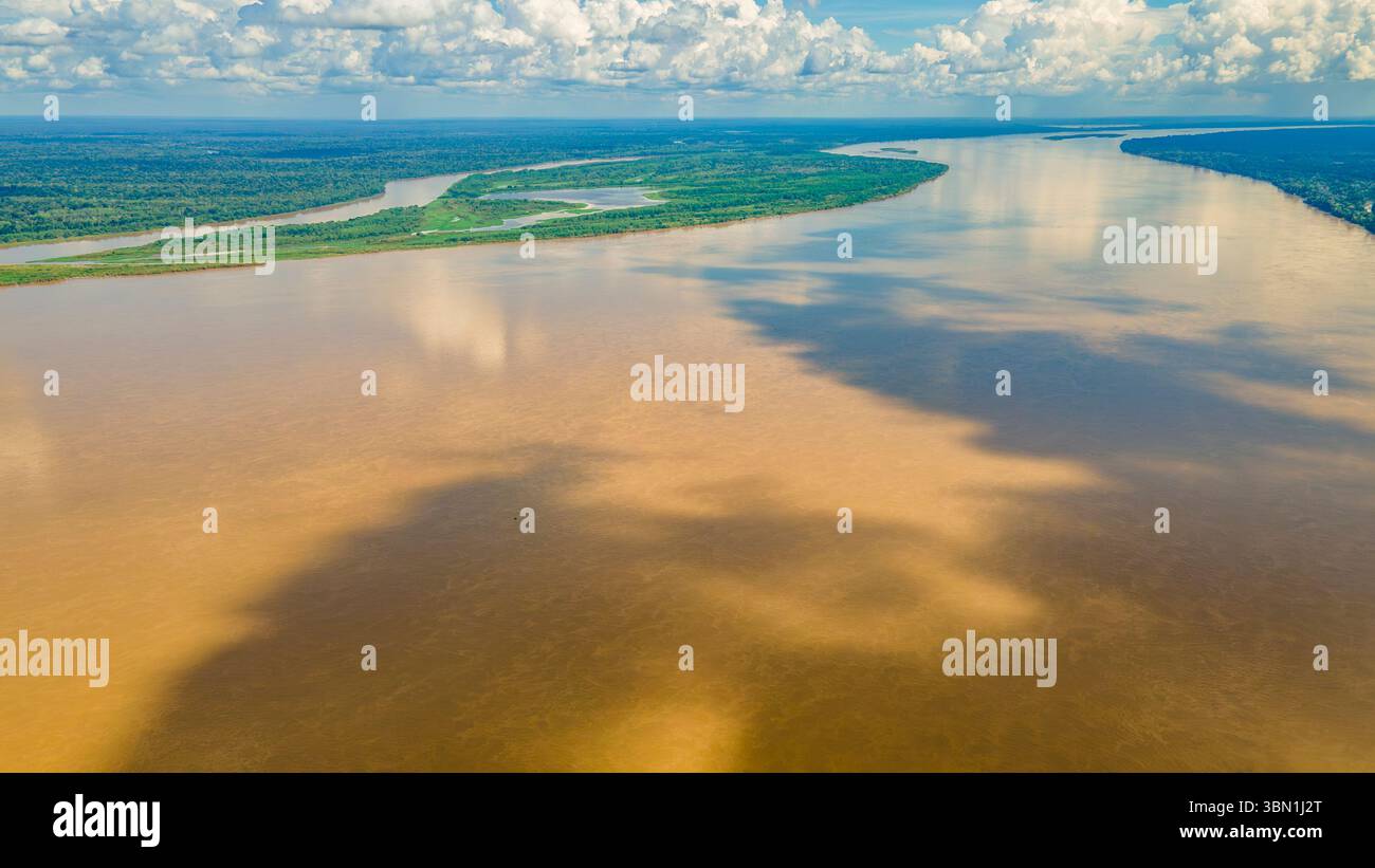 Una vista aerea mozzafiato del Rio delle Amazzoni con vegetazione lussureggiante sulle rive, che mostra i colori unici dell'acqua e i cieli vibranti di Amazonas, Colombia. Foto Stock