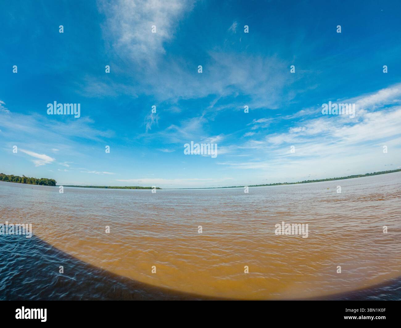 Una vista serena del Rio delle Amazzoni con un cielo blu vibrante, raffigurato a Leticia, Amazonas, Colombia. Perfetto per la natura e gli appassionati di viaggi. Foto Stock