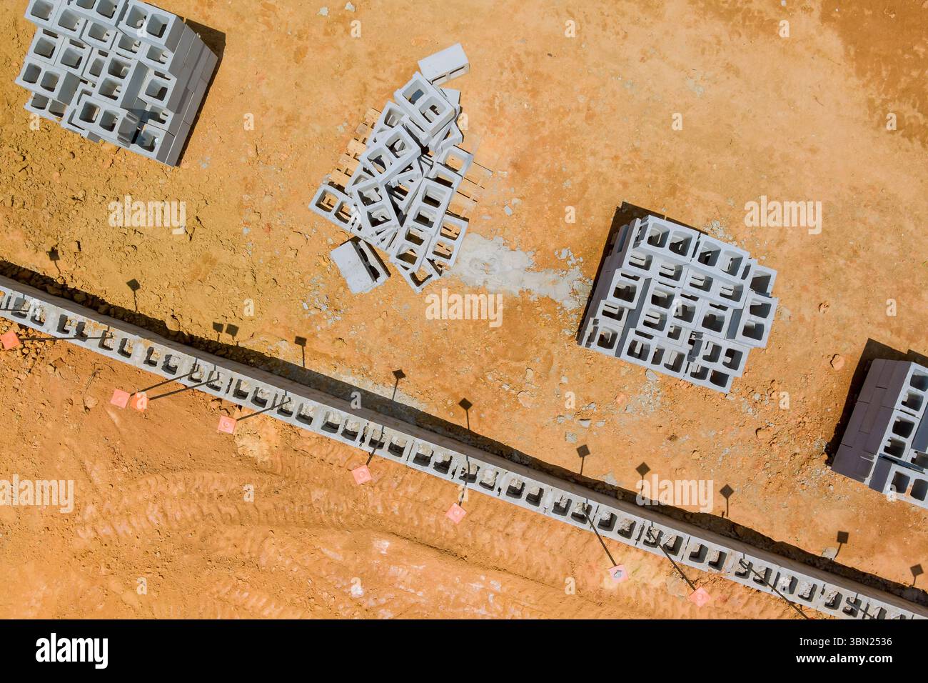 Vista aerea del cantiere con pile di blocchi di cemento su terreni polverosi durante la giornata lavorativa Foto Stock