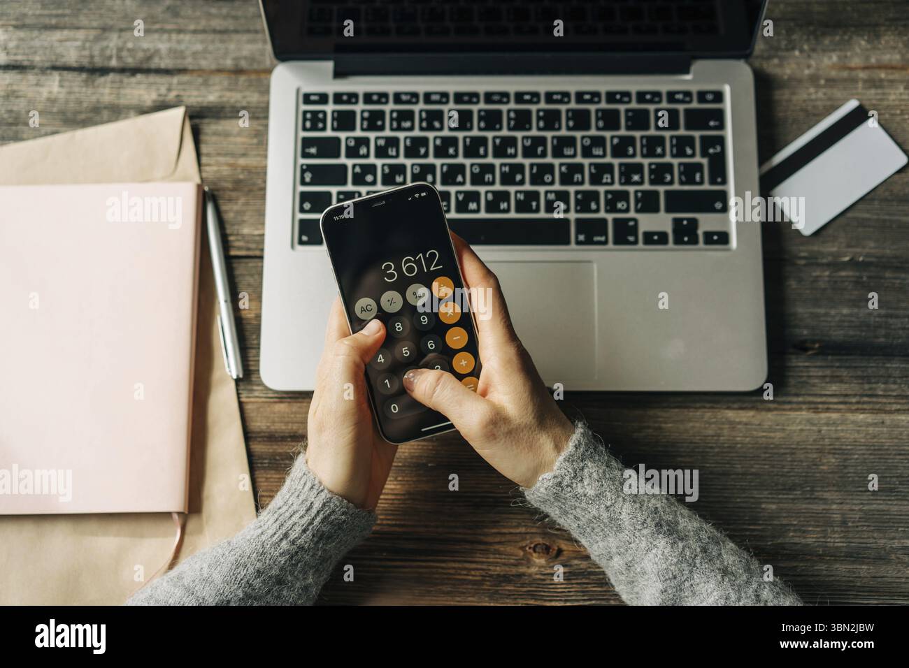 Nahaufnahme einer Frau, Die mit einem Taschenrechner auf einem Telefonbildschirm rechnet Foto Stock