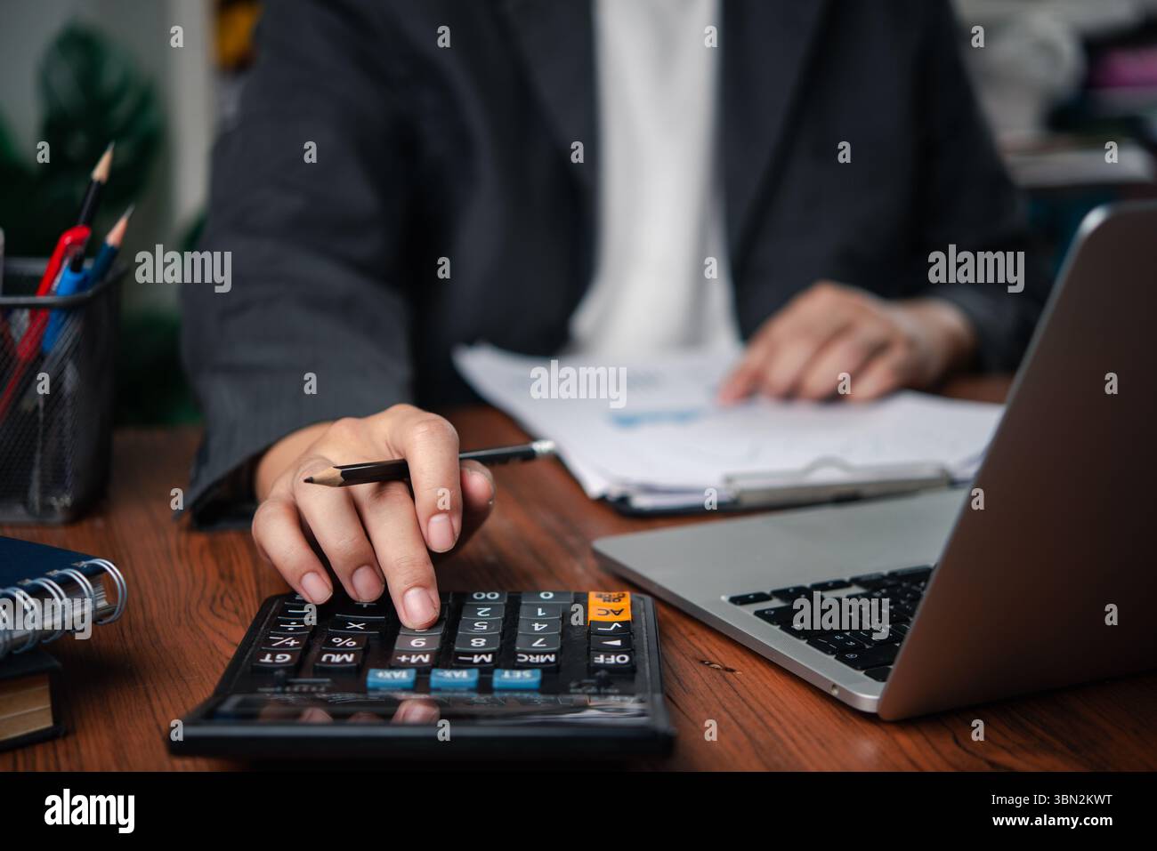 Persona commerciale che analizza i dati finanziari con documenti cartacei e laptop, mostrando il calcolo, la gestione delle spese e la rendicontazione finanziaria. contabilità, budg Foto Stock