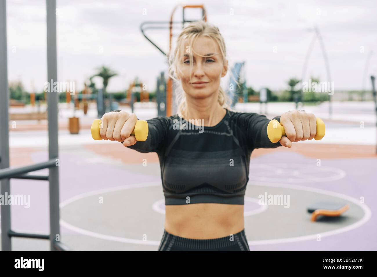 Giovane atleta che fa esercizi con manubri sul campo sportivo Foto Stock