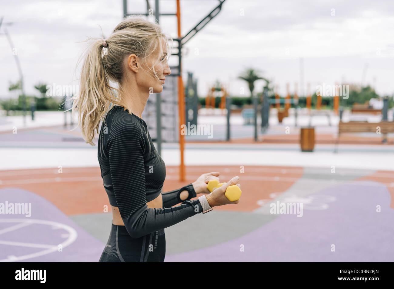 Donna sportiva in allenamento con manubri all'aperto Foto Stock