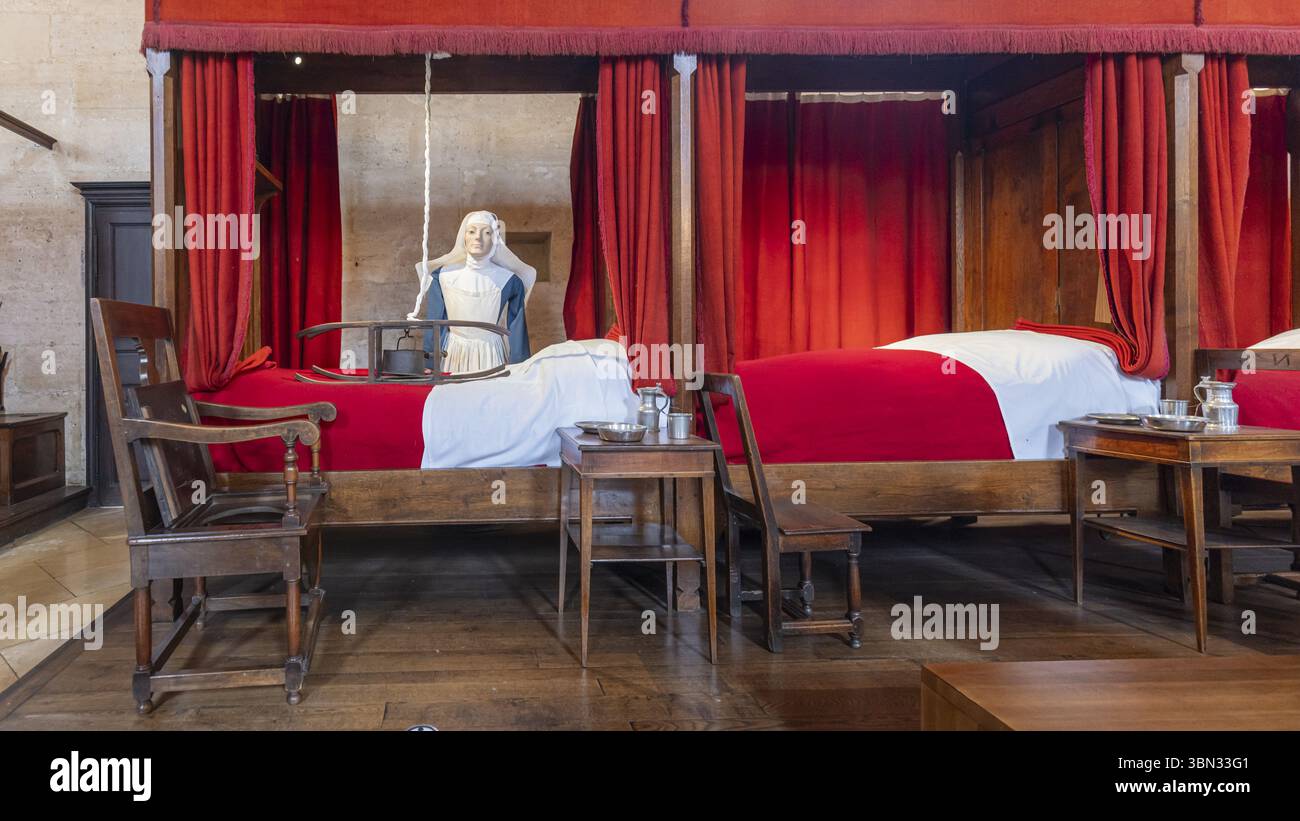 Beaune, Francia - 29 aprile 2024: Scenario di infermiere con letti rossi presso Hospices de Beaune o Hotel-Dieu de Beaune, un ex almshouse di beneficenza in antico a. Foto Stock