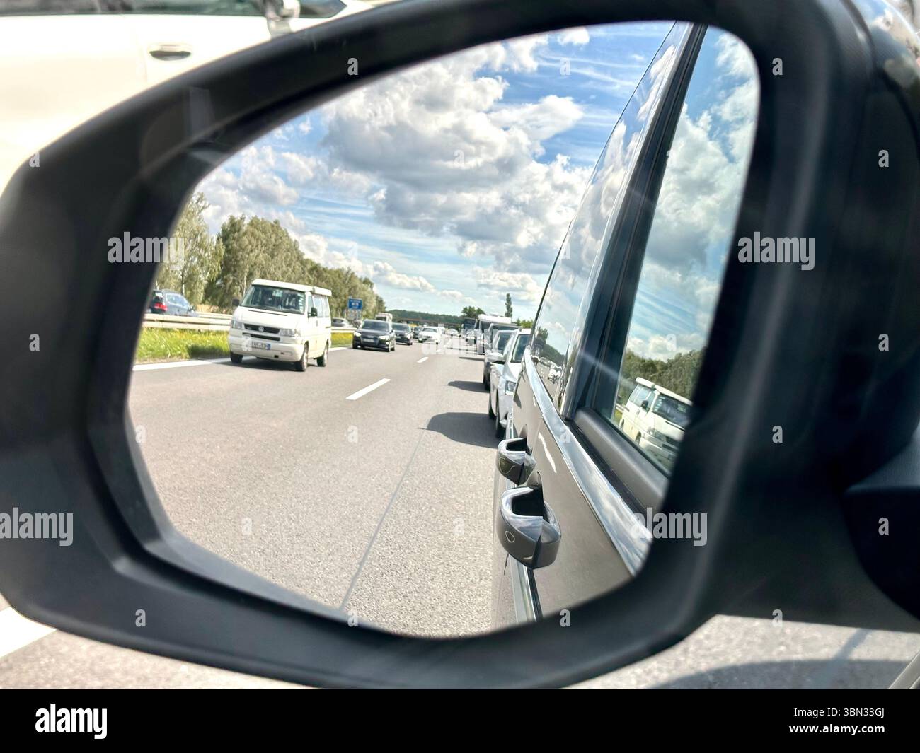 Una vista dallo specchio di visione laterale di un'auto in un corridoio di emergenza formato da auto in un ingorgo stradale - Immagine stock catturata con smartphone