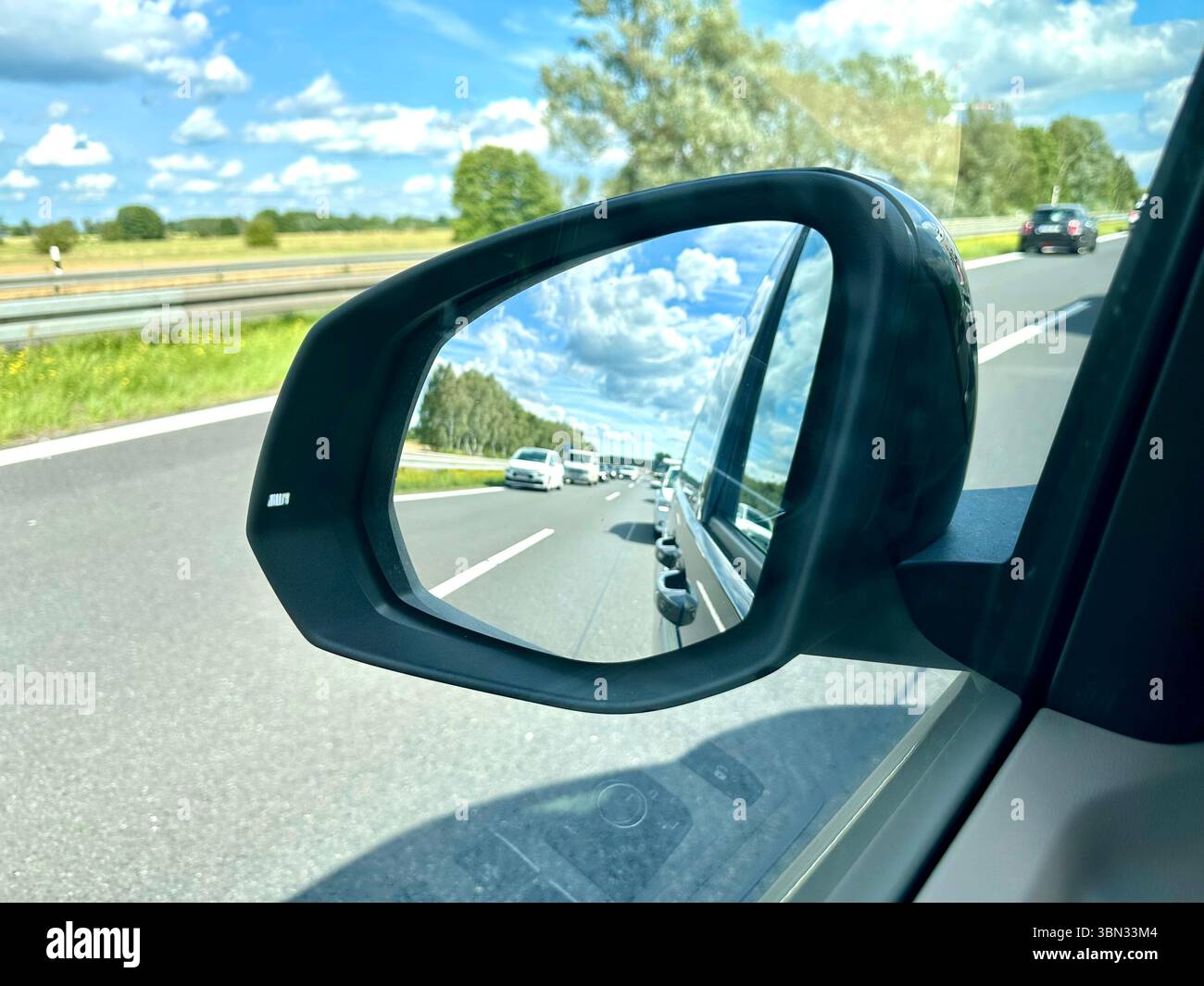 Una vista dallo specchio di visione laterale di un'auto in un corridoio di emergenza formato da auto in un ingorgo stradale - Immagine stock catturata con smartphone