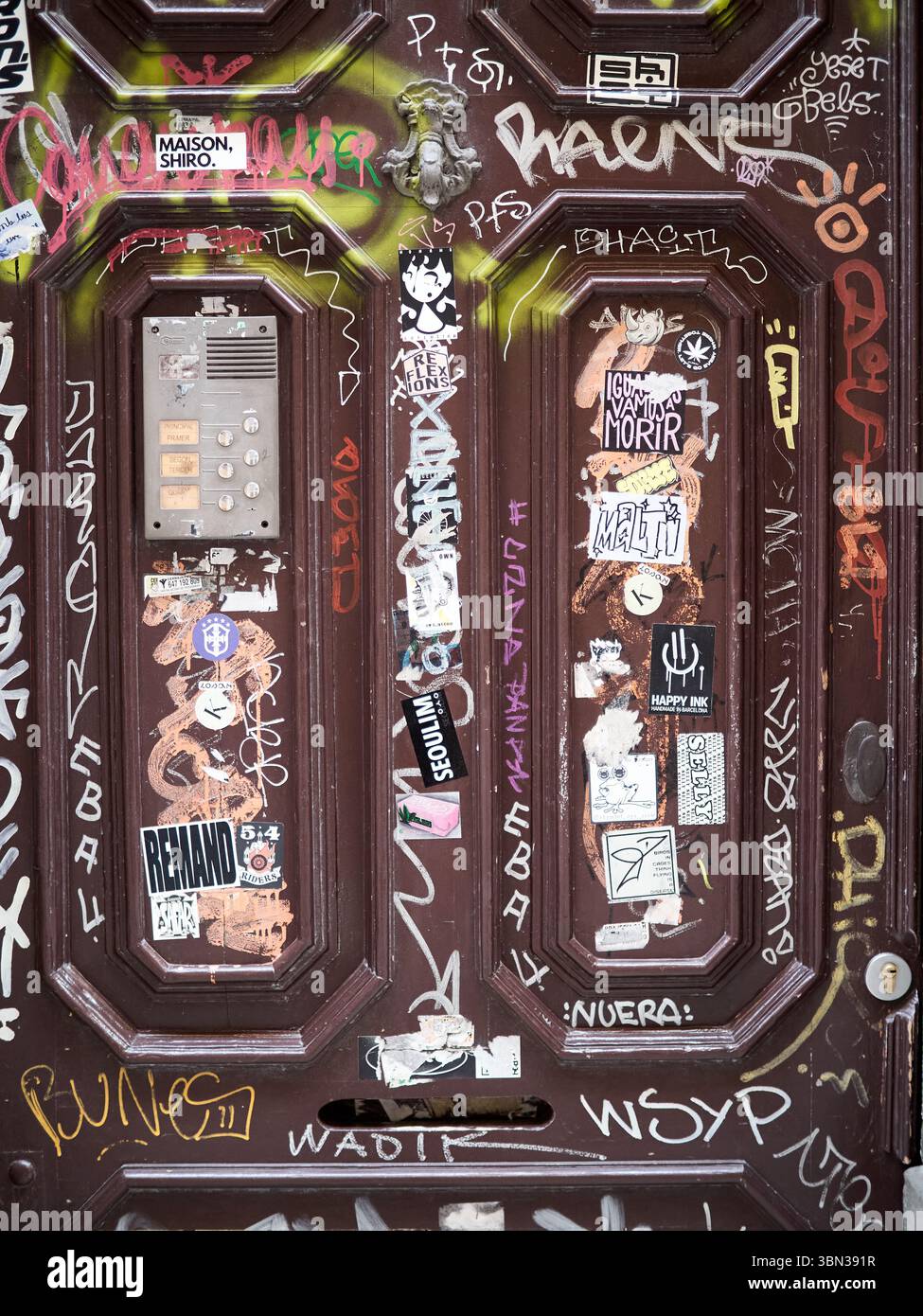 Vecchia porta di Barcellona coperta da graffiti, adesivi ed etichette urbane. L'immagine cattura un mix di Street art e espressione giovanile, con vib Foto Stock
