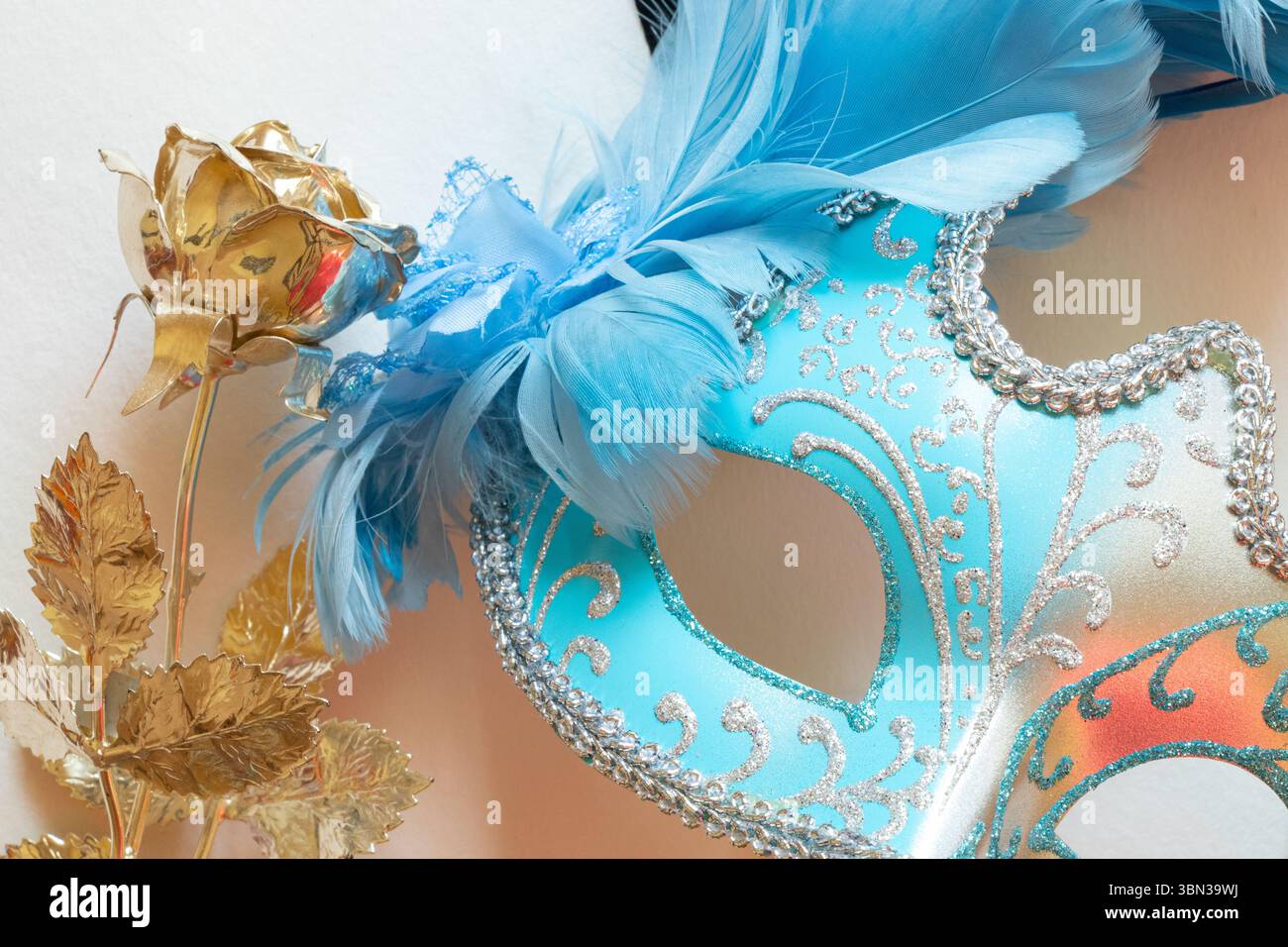 Maschera di carnevale azzurra con piume blu e nere e rosa dorata su sfondo bianco, accessorio decorativo per mascherare Foto Stock