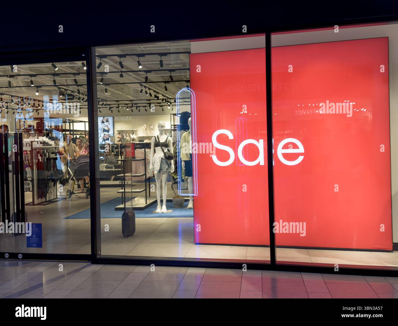Insegna di vendita gigante visualizzata sul muro rosso dietro le vetrine del negozio Nike Sports Fashion Store di Londra, Regno Unito Foto Stock