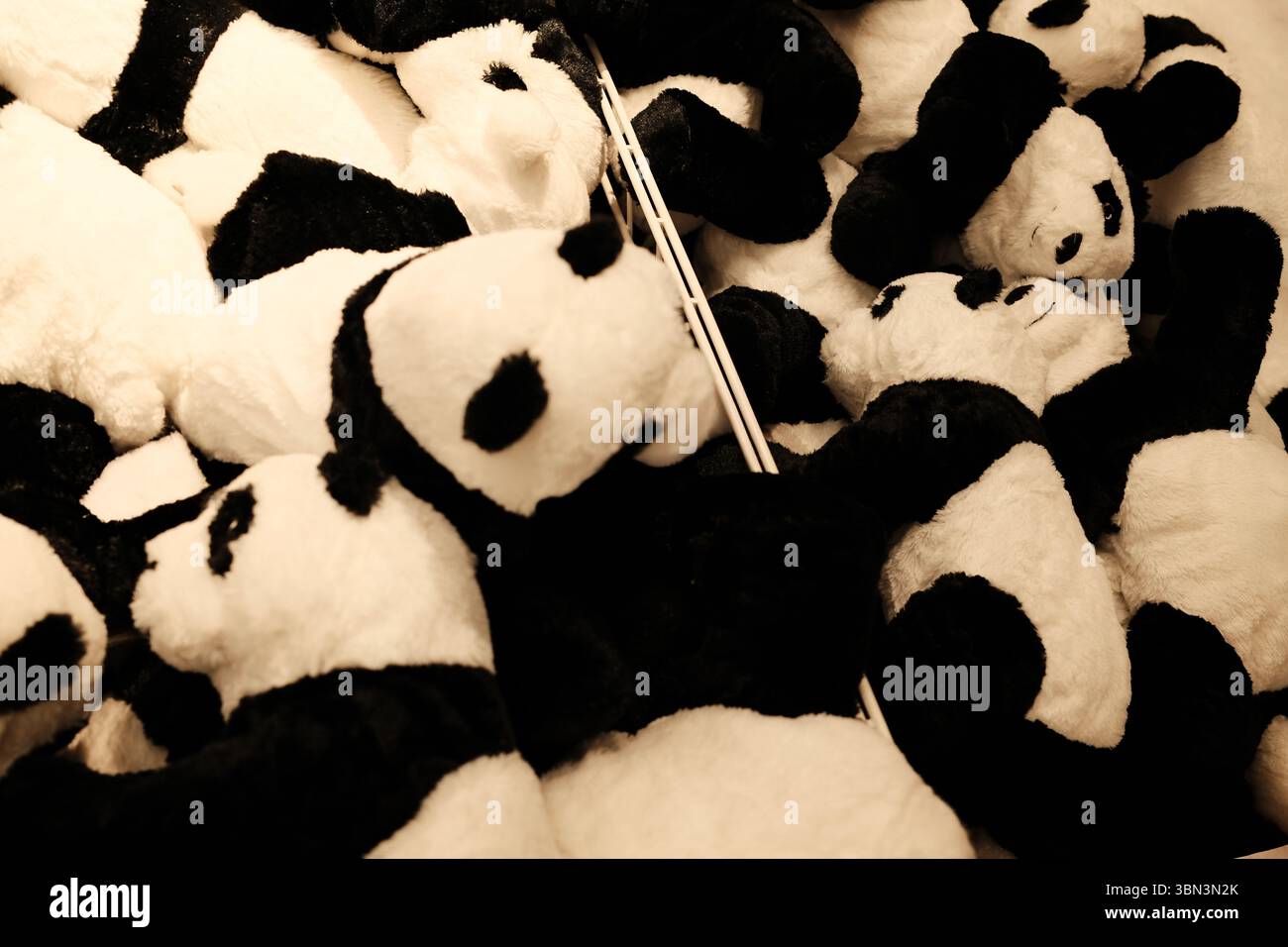 Una grande pila di peluche di panda bianchi e neri riempie un cestino in un negozio di giocattoli. Morbido e affascinante, ideale per i bambini Foto Stock