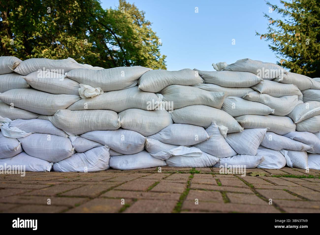 File di sacchi di sabbia impilati come barriera contro le inondazioni sulla strada della città. Misura di protezione di emergenza per evitare danni causati dall'acqua in caso di tempeste, pioggia intensa o inondazioni Foto Stock