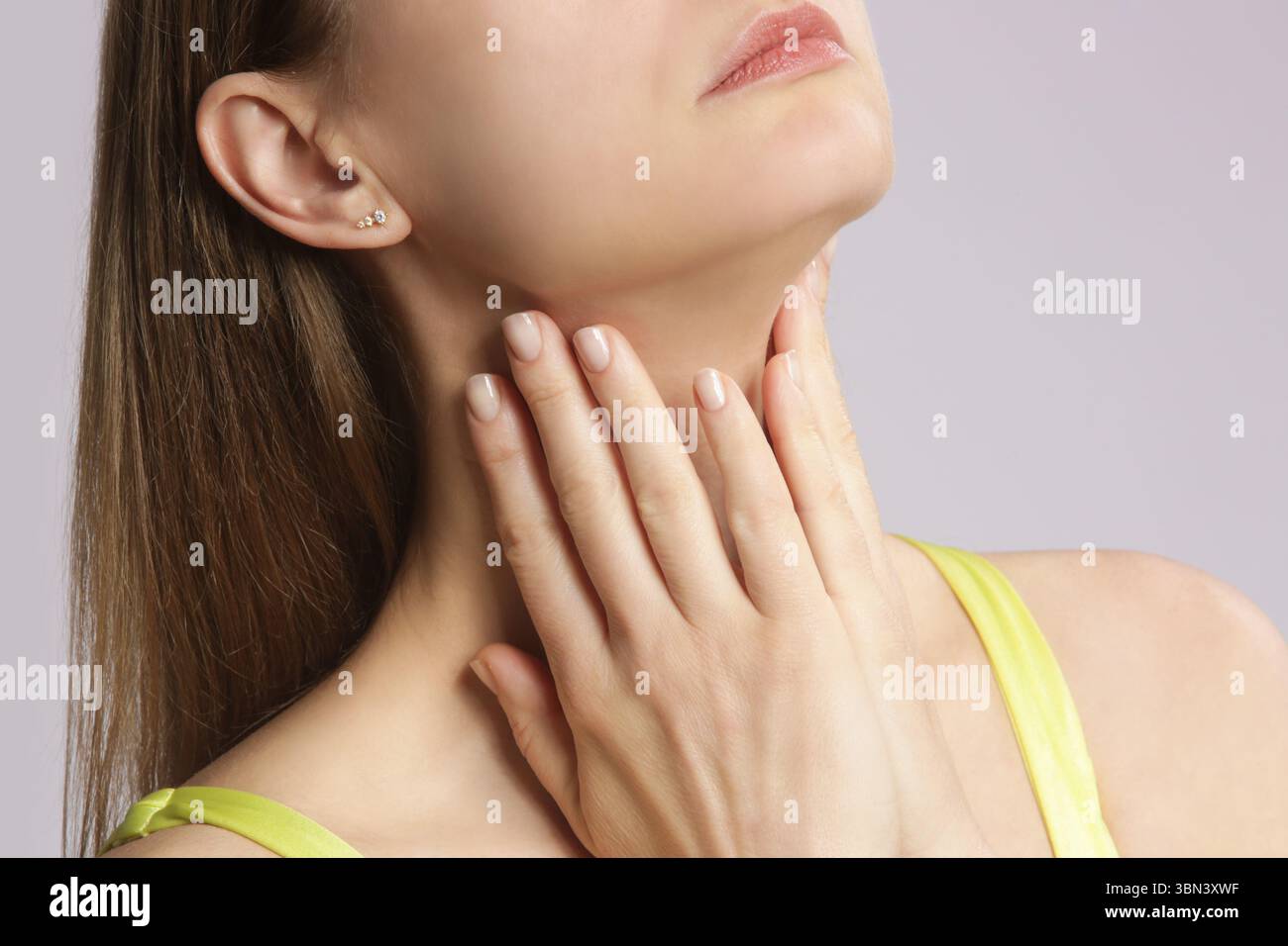 Donna caucasica che si tocca la gola. Mal di gola, raffreddore, influenza, tonsillite o problema della ghiandola tiroidea Foto Stock