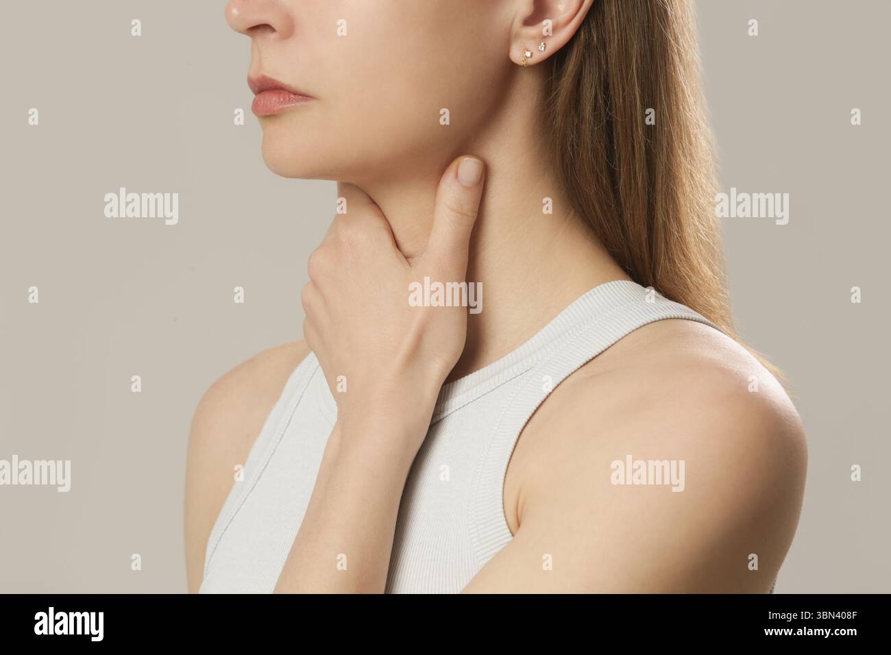 Donna caucasica che si tocca la gola. Mal di gola, raffreddore, influenza, tonsillite o problema della ghiandola tiroidea Foto Stock