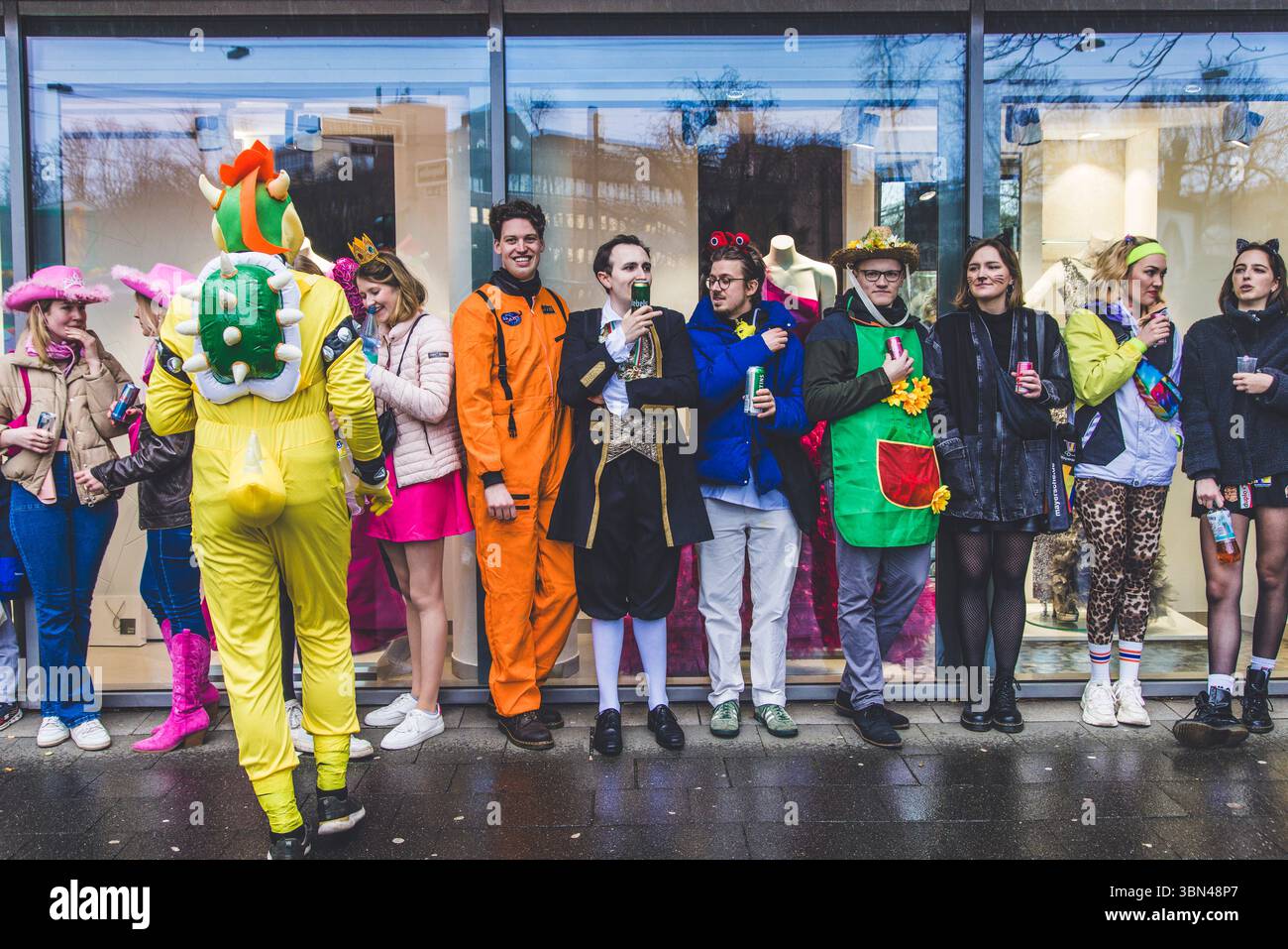 Germania, Düsseldorf, carnevale, gruppo di giovani che aspettano sotto la pioggia Foto Stock