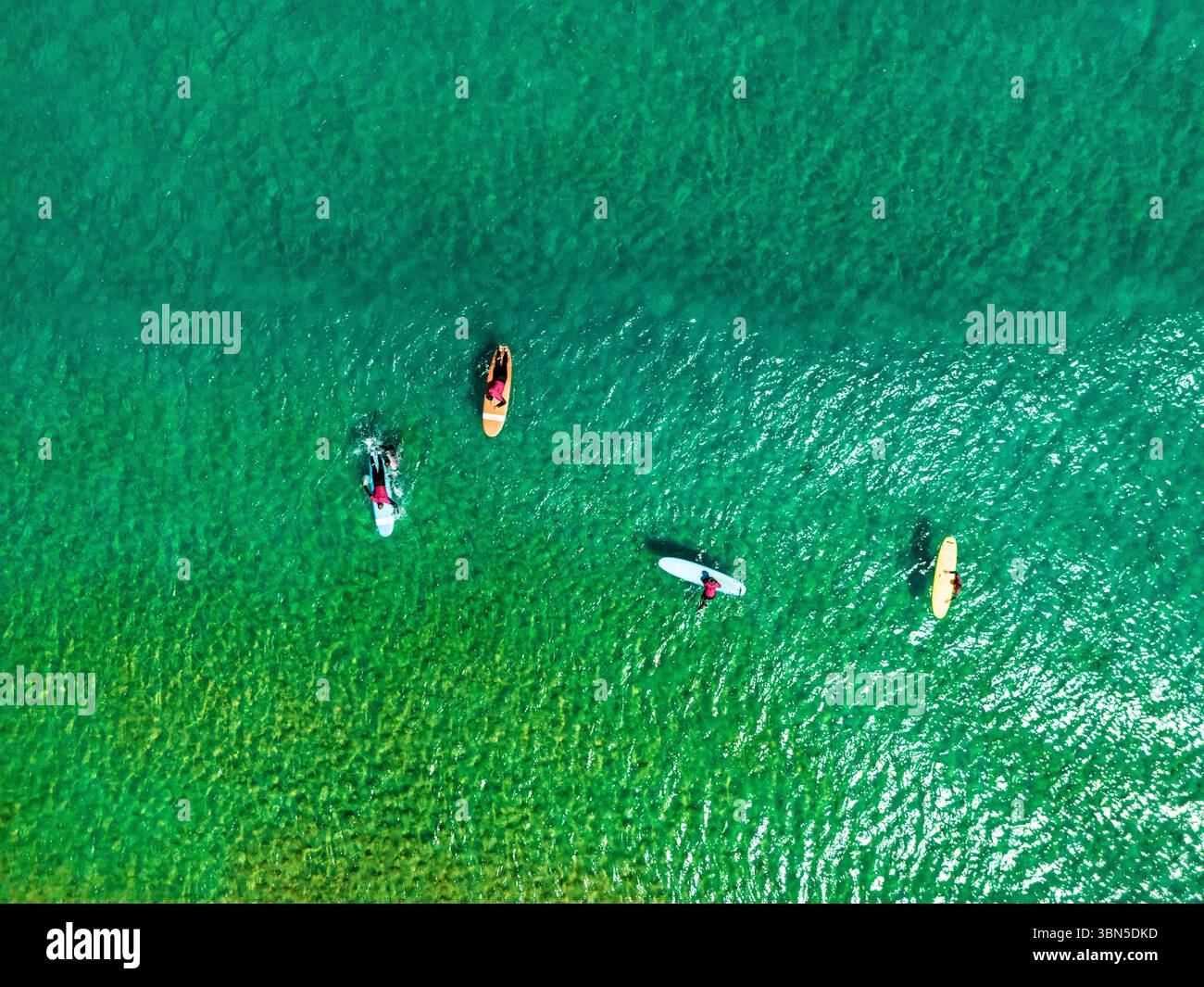 Una vista aerea mostra diverse persone che si divertono in stand-up paddleboard nelle limpide acque turchesi, probabilmente per attività ricreative ed esercizio fisico. Foto Stock