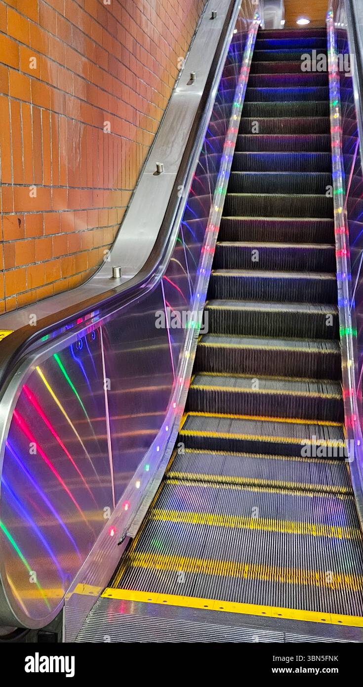 Scala mobile colorata illuminata da LED in una stazione della metropolitana di San Francisco, che unisce design moderno e funzionalità urbana in un vivace ambiente sotterraneo. Foto Stock