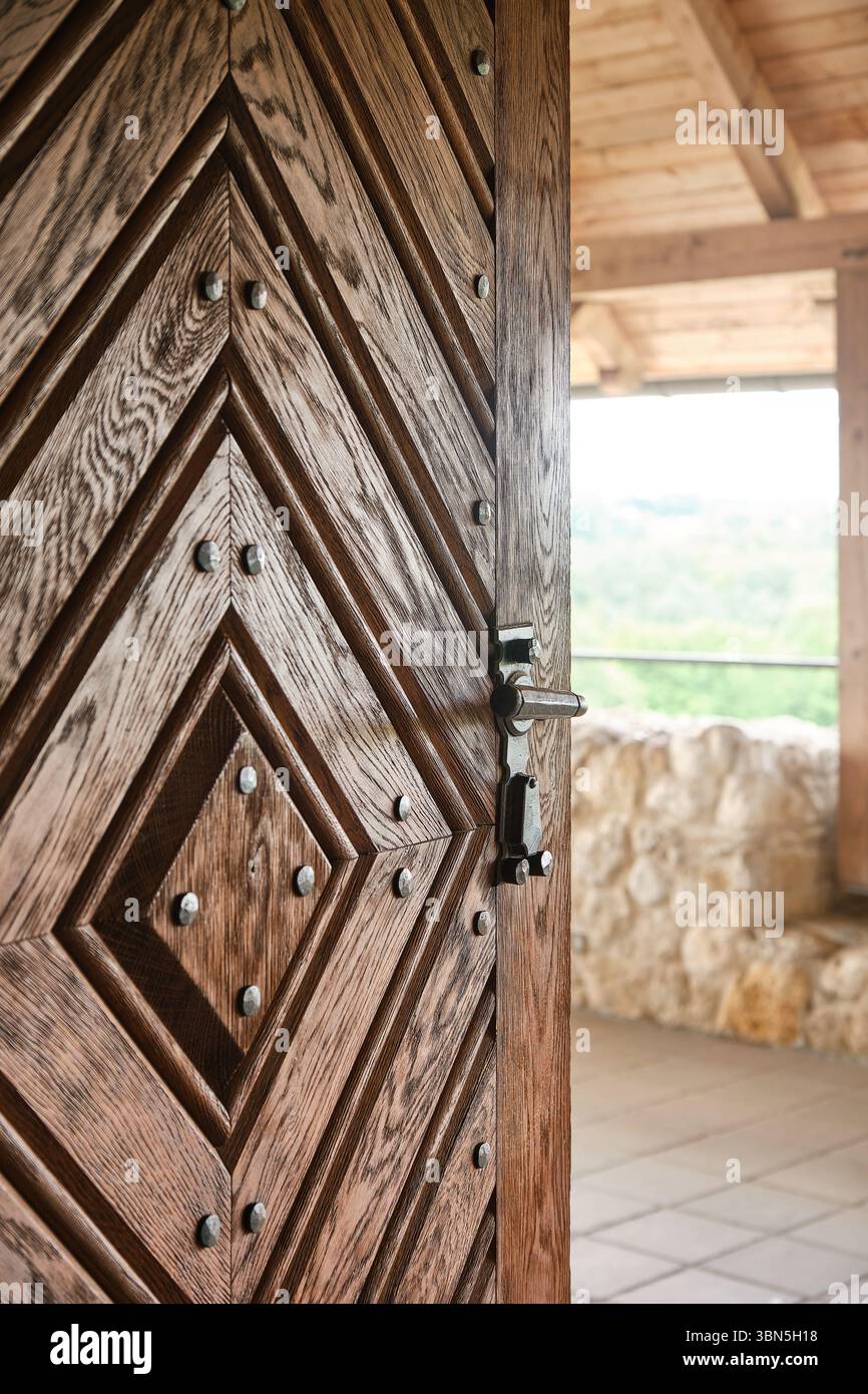 Primo piano dettagliato di una porta in legno tradizionale con motivo geometrico e borchie in ferro, che mettono in risalto l'artigianato rustico e la struttura architettonica Foto Stock