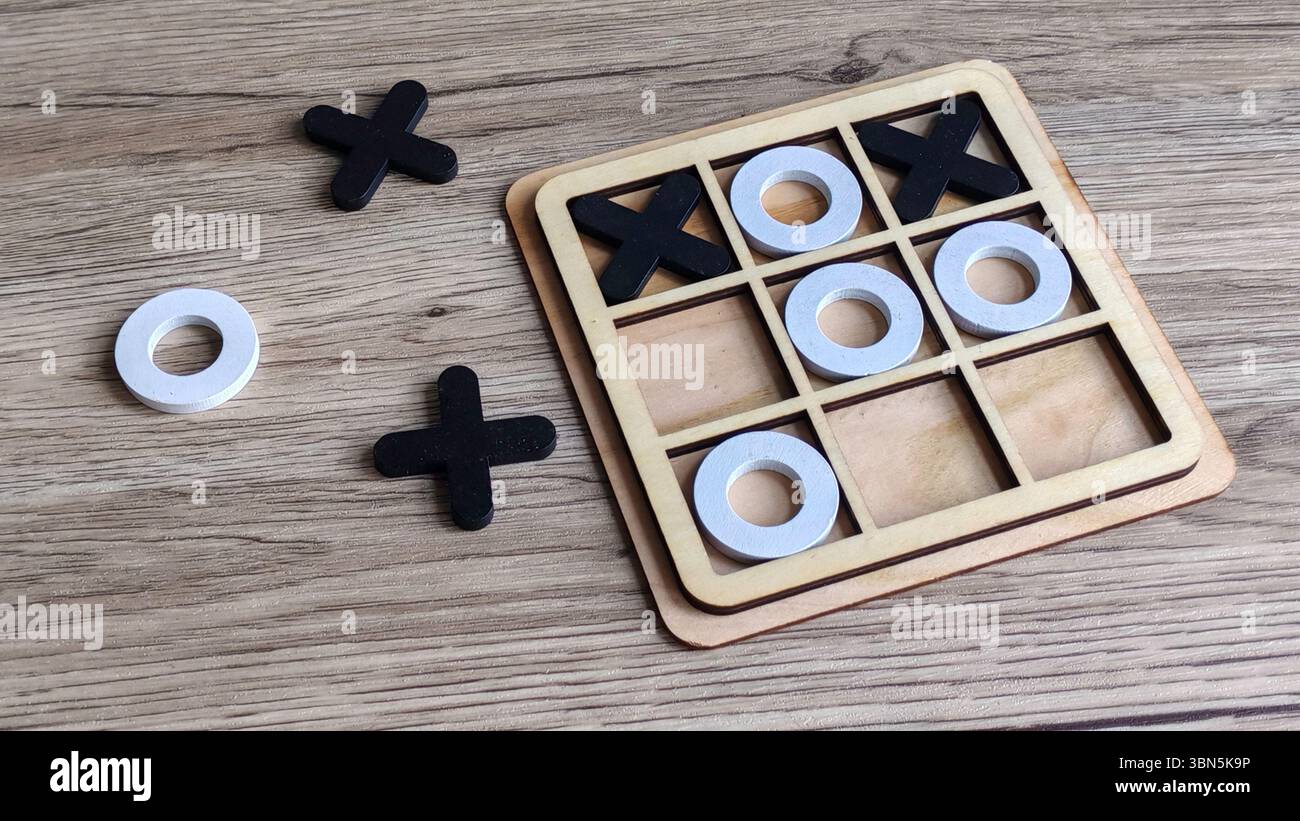 Gioco in legno TIC-TAC-Toe con pezzi X e o sul tavolo, simbolo di strategia, giochi e competizione Foto Stock