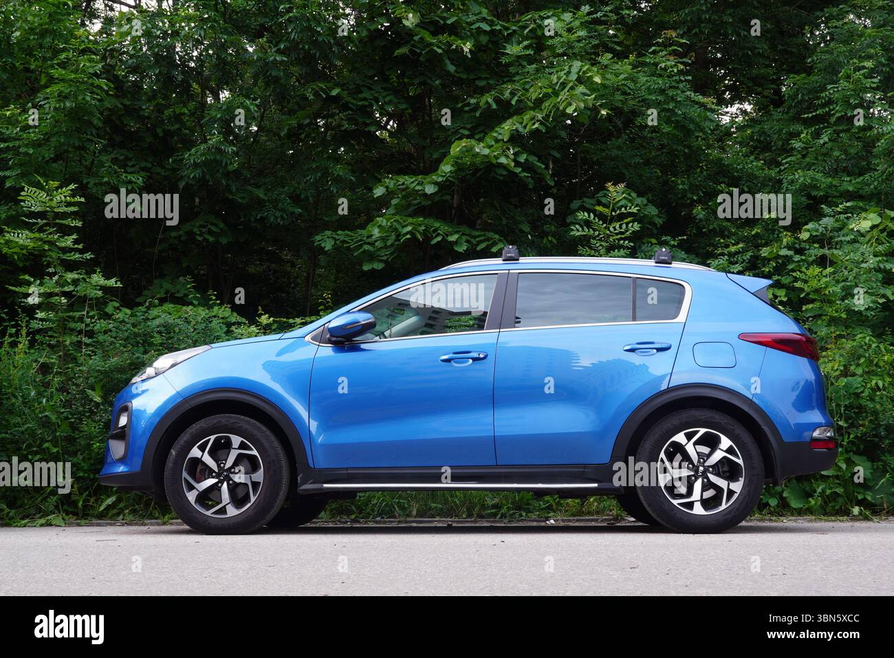 Bucarest, Romania – 1° giugno 2025: Vista ravvicinata dell'auto blu KIA Sportage parcheggiata su strada lungo la foresta in estate Foto Stock
