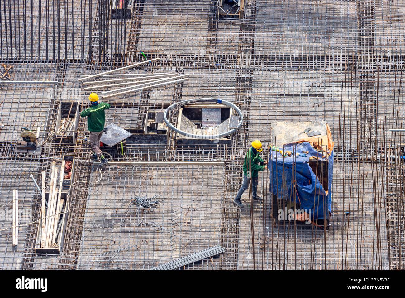 Lavoratori edili che indossano giubbotti di sicurezza ed elmetti che lavorano su un telaio di costruzione. Foto Stock