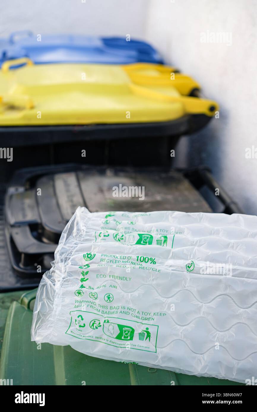 Cuscino d'aria in plastica realizzato in materiale riciclato con simboli ecologici e testo. Contenitori per rifiuti o contenitori per rifiuti accanto. Foto Stock