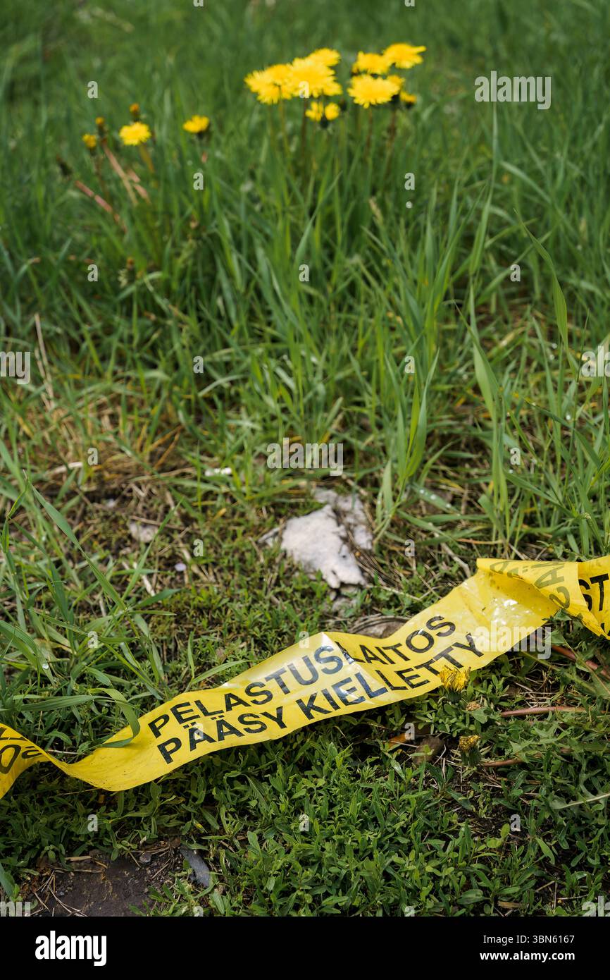 Nastro giallo su erba con testo in finlandese: Pelastuslaitos Pääsy Kielletty (servizi di emergenza - nessun ingresso). Foto Stock