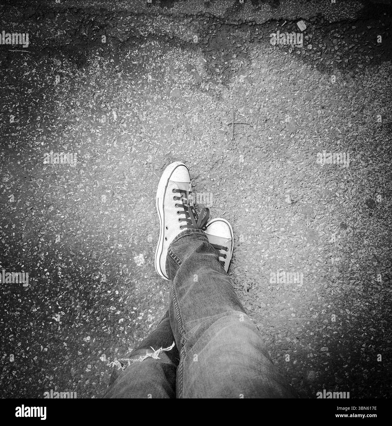 Vista ad angolo alto delle gambe da uomo medio-adulte che indossano jeans e sneakers Foto Stock