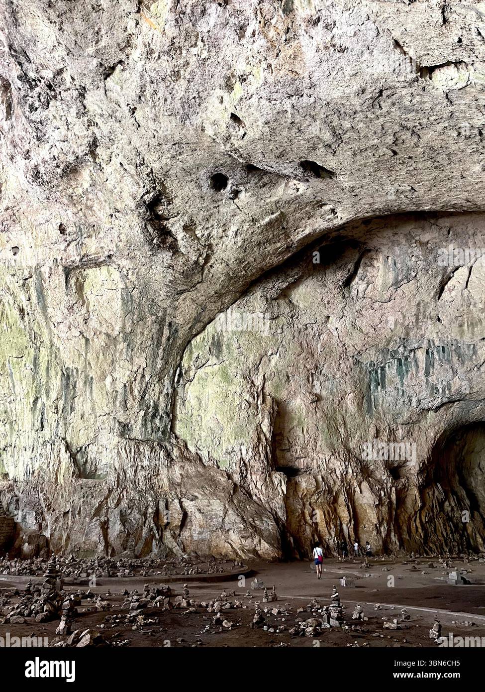 I viaggiatori che si trovano sotto l'enorme cupola naturale della grotta Devetashka in Bulgaria, uno spettacolare sito geologico nei Balcani, nell'Europa orientale Foto Stock