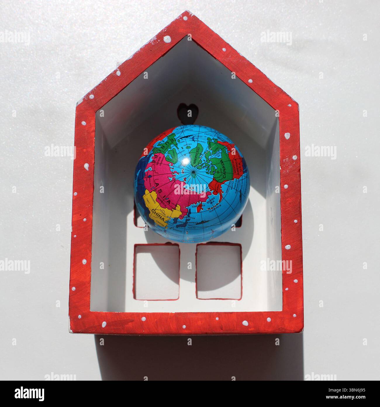 Toy Globe all'interno di Toy Hollow House su superficie bianca. Foto stock per l'illustrazione della scelta di un luogo in cui vivere Foto Stock