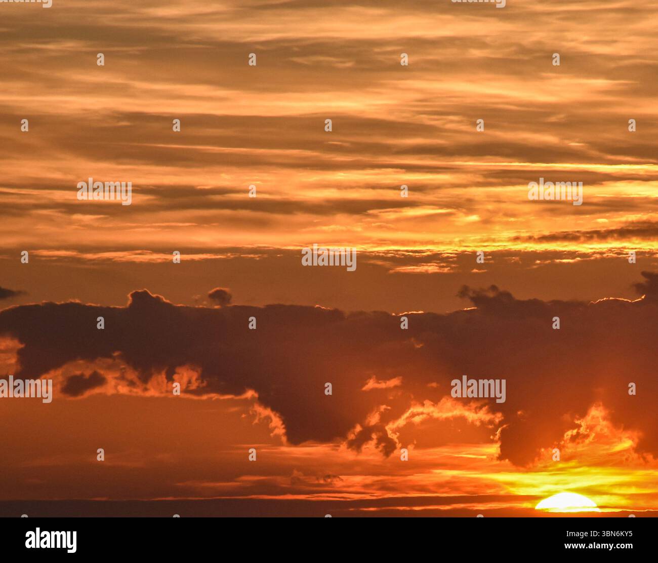 Cielo serale colorato con luce del tramonto che si riflette sulle nuvole, creando una sfumatura luminosa dall'oro al blu tenue Foto Stock