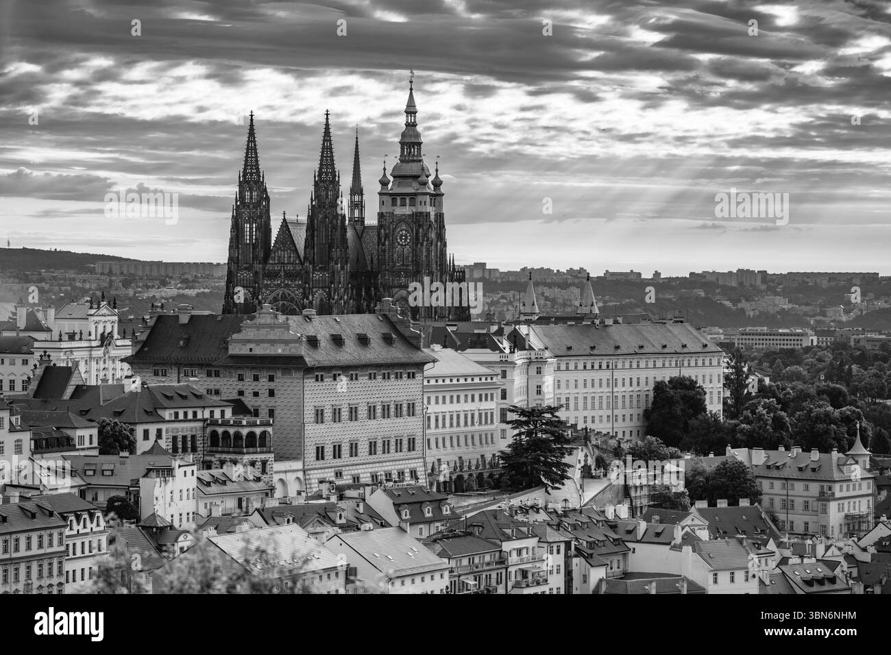 La prima luce dell'alba proietta un soffice bagliore sul Castello di Praga, evidenziando le sue maestose torri. La città si risveglia quando la luce del sole si irrompe tra le nuvole, creando un'atmosfera magica. Foto Stock