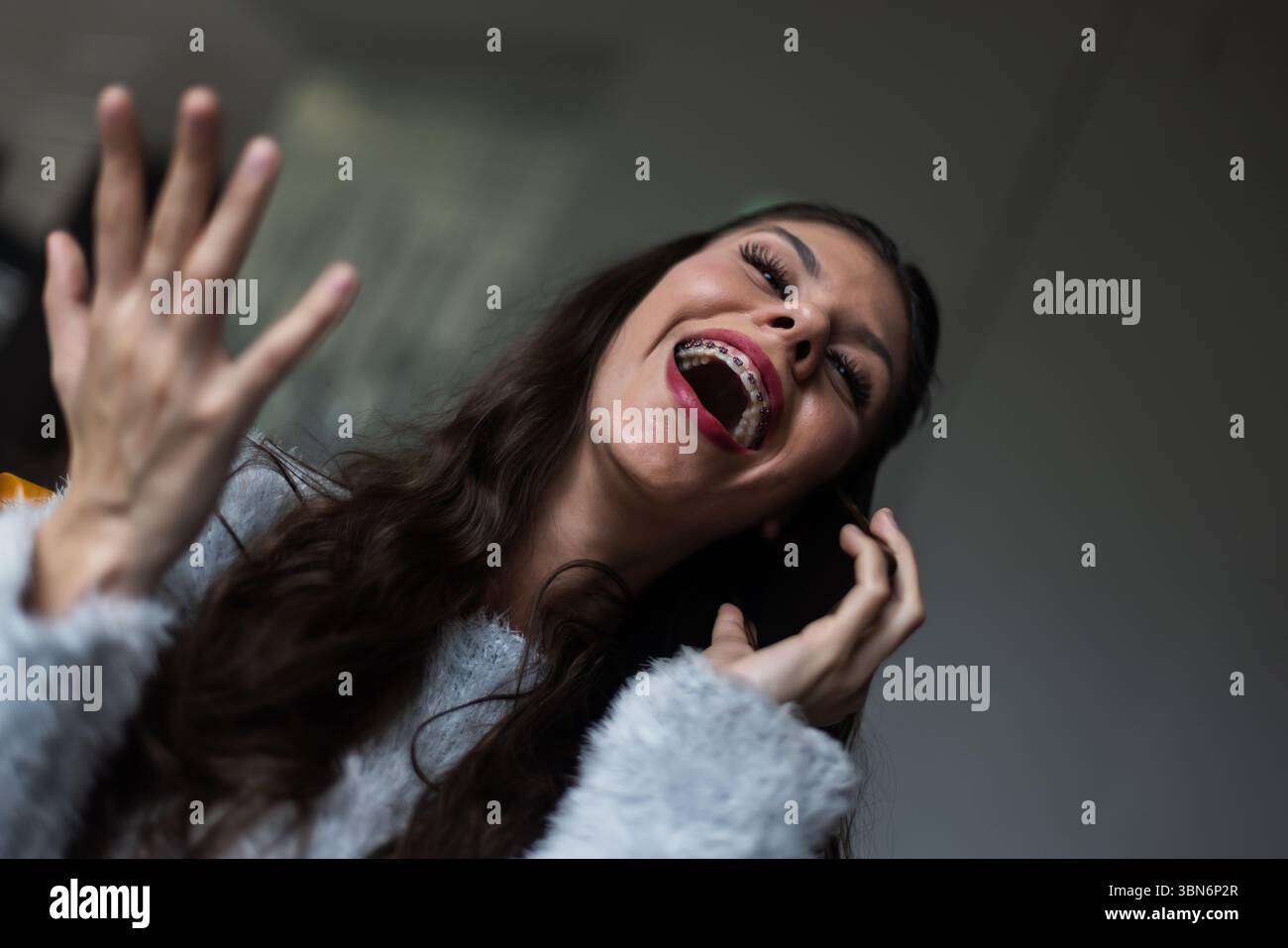 Una donna allegra con l'apparecchio che ride con le mani vicino al viso, catturata in un momento casuale trasmettendo felicità e sicurezza. Foto Stock Una donna allegra con l'apparecchio che ride con le mani vicino al viso, catturata in un momento casuale trasmettendo felicità e sicurezza. Foto Stock