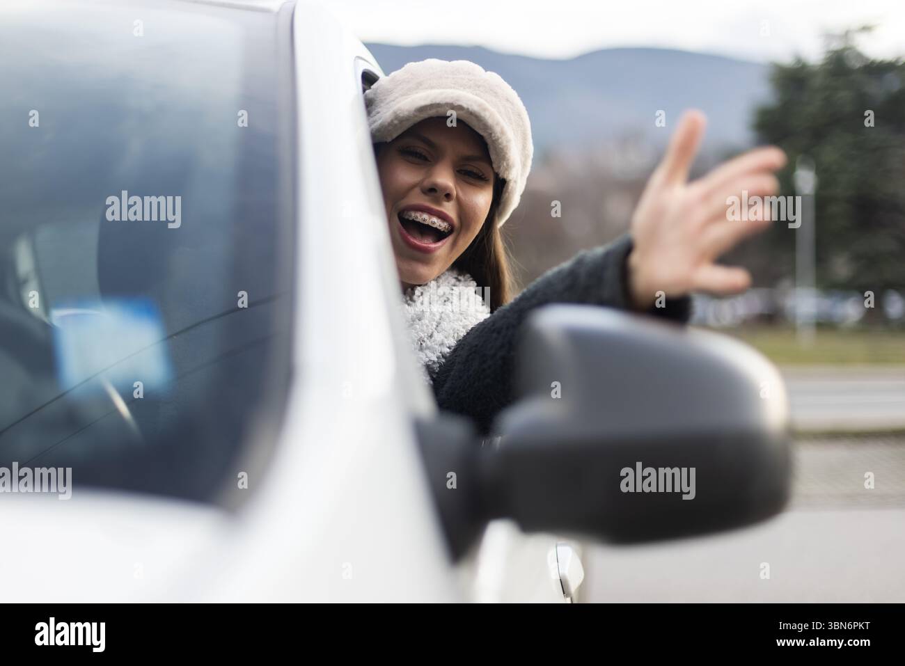 Una donna irritata che si sporge dal finestrino di un'auto mentre urla, esprimendo rabbia. Cattura un momento di emozione umana e interazione all'interno del contesto Foto Stock