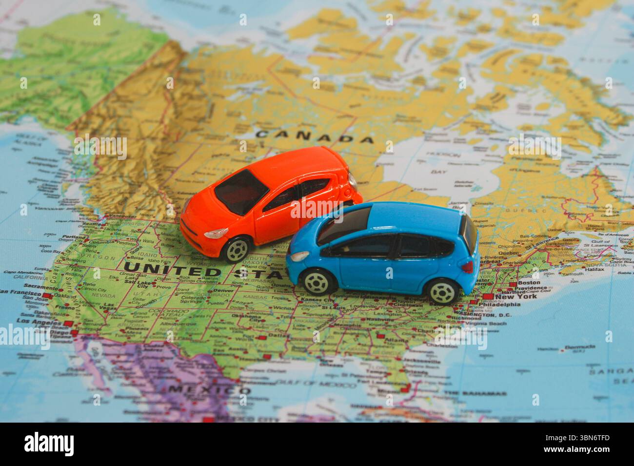 Due colorate macchinine giocattolo sulla mappa del Nord America che simboleggiano la pianificazione del viaggio, l'avventura su strada e il noleggio auto negli Stati Uniti e in Canada. Foto Stock