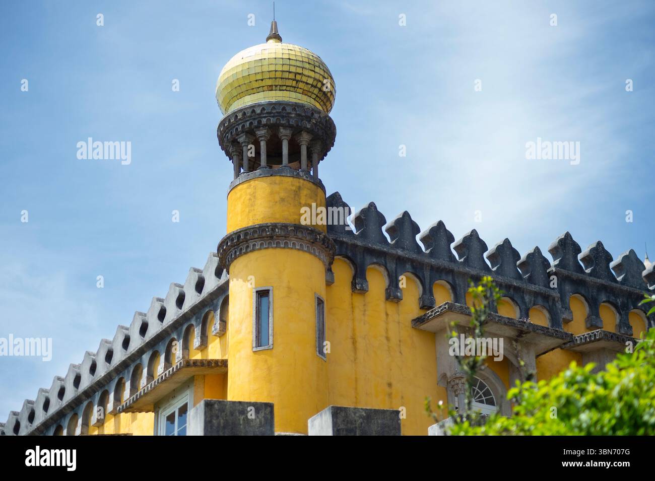 Il maestoso Palácio da pena a Sintra, in Portogallo, con le sue distintive pareti gialle e la cupola dorata. Architettura da favola sotto un cielo vibrante. Foto Stock