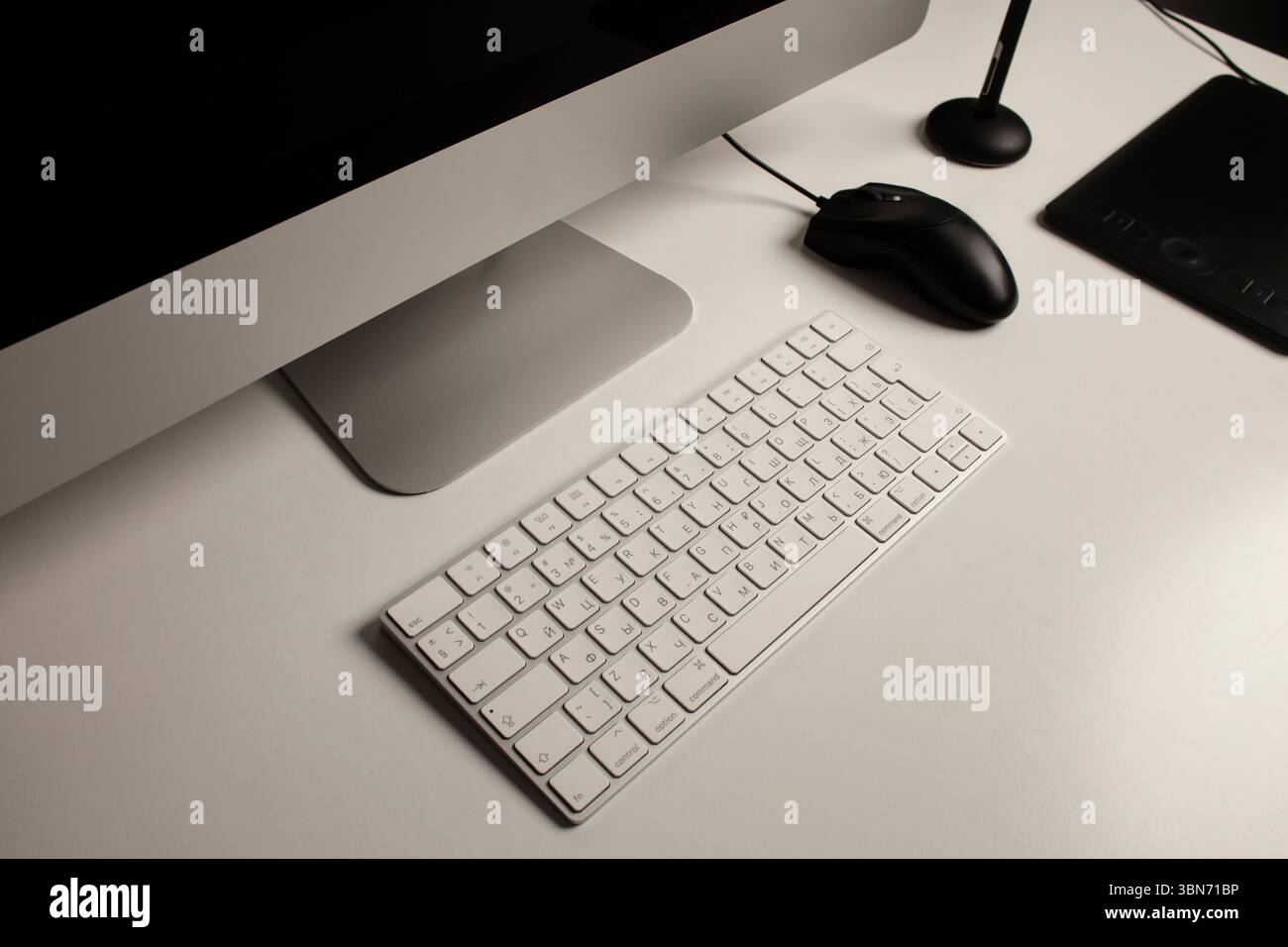 Spazio di lavoro minimalista per l'ufficio domestico con un computer desktop, una tastiera, un notebook, un tablet con penna su una scrivania bianca e pulita. Freelance a casa. Arte a casa. Foto Stock