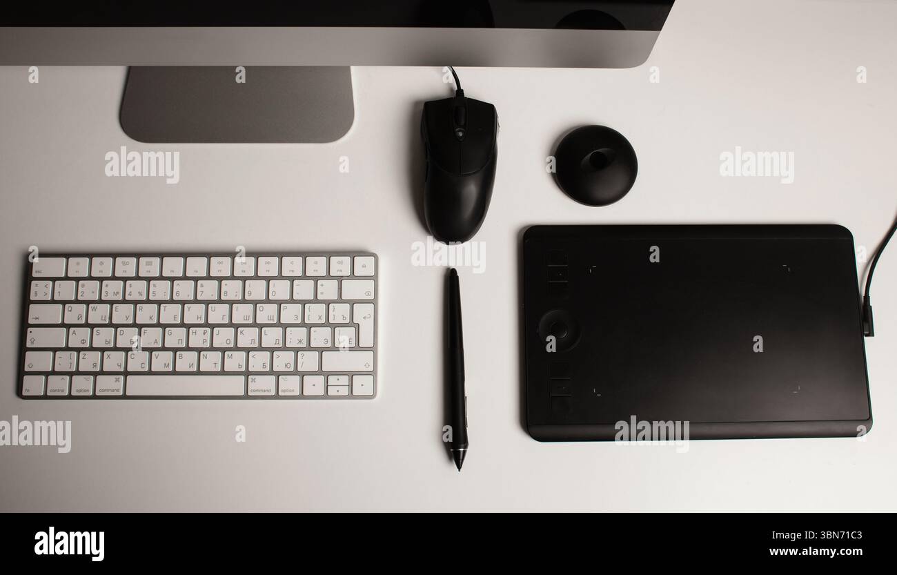 Spazio di lavoro minimalista per l'ufficio domestico con un computer desktop, una tastiera, un notebook, un tablet con penna su una scrivania bianca e pulita. Freelance a casa. Arte a casa. Foto Stock
