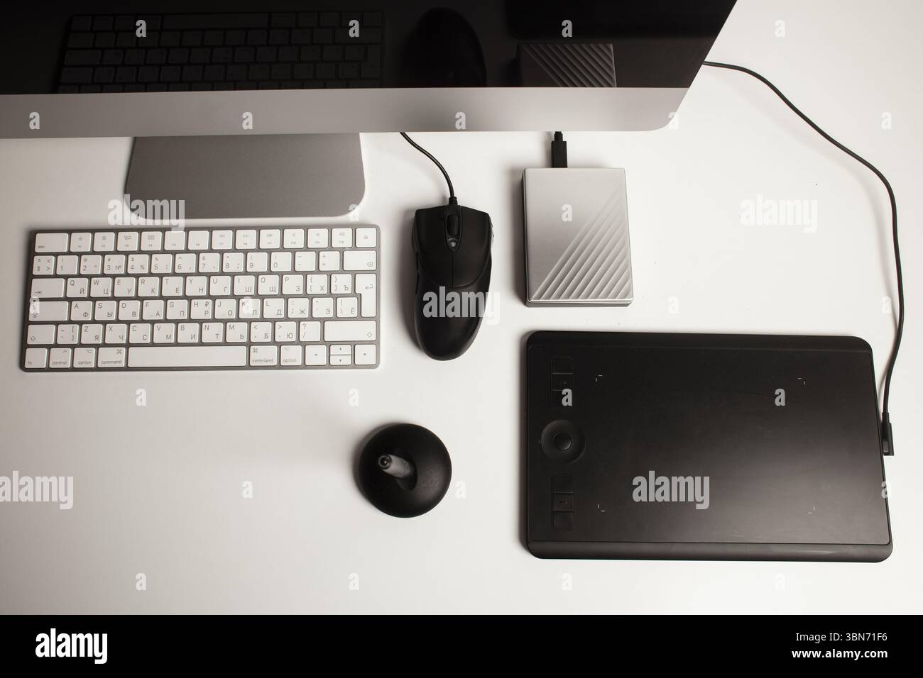 Spazio di lavoro minimalista per l'ufficio domestico con un computer desktop, una tastiera, un notebook, un tablet con penna su una scrivania bianca e pulita. Freelance a casa. Arte a casa. Foto Stock
