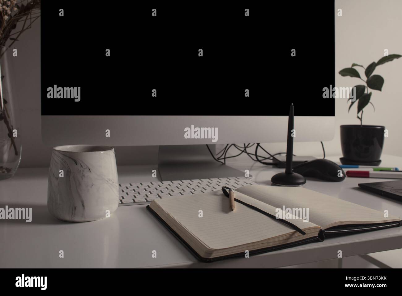 Spazio di lavoro minimalista per l'ufficio domestico con computer desktop, tastiera, notebook, tavoletta grafica, tazza con tè su una scrivania bianca pulita. Foto Stock