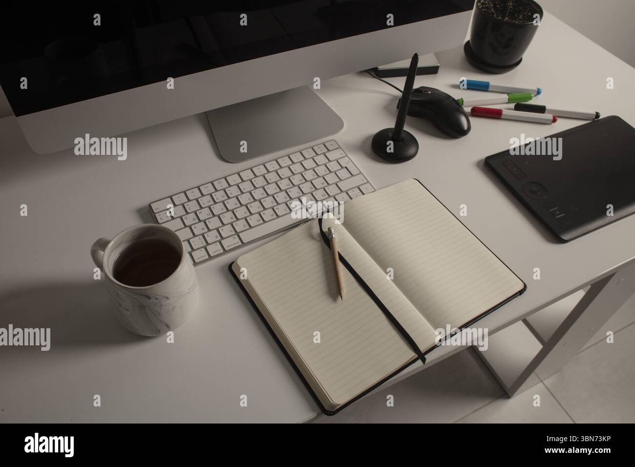 Spazio di lavoro minimalista per l'ufficio domestico con computer desktop, tastiera, notebook, tavoletta grafica, tazza con tè su una scrivania bianca pulita. Foto Stock