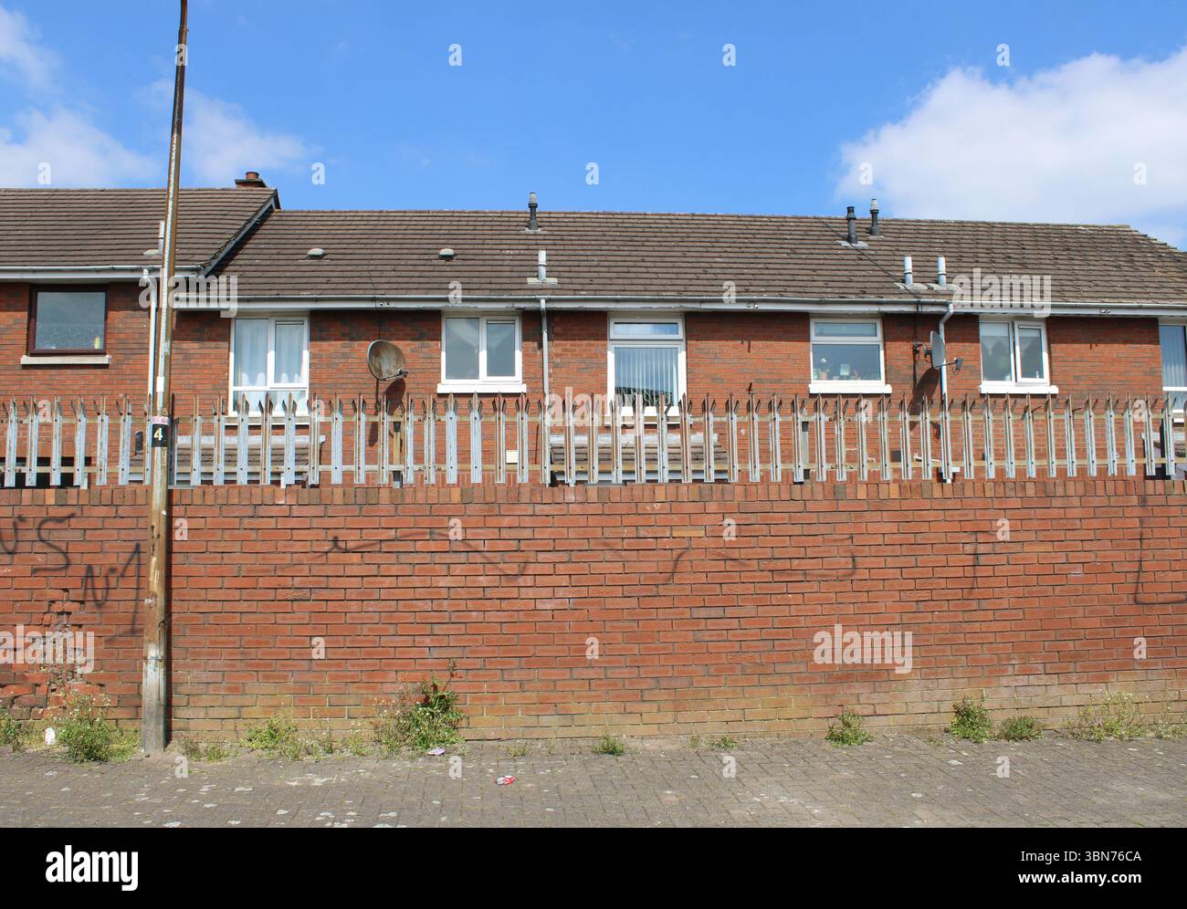 Rowhouses dietro un muro di pace in mattoni a spillo a Belfast, Irlanda del Nord Foto Stock